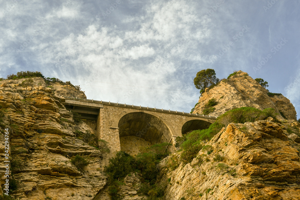 View from below of the cliff on the port of Alassio with the arches supporting the Aurelian Drive, Liguria, Italy