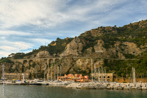 Scenic view of the harbor with moored boats and the Aurelian Drive on the cliff, Alassio, Liguria, Italy photo