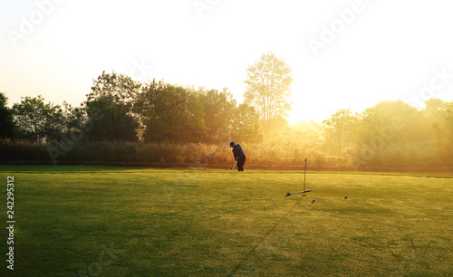 Golfer is chipping golf ball on the green for practice , morning time