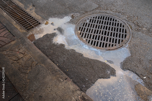 Sewer lid on street with dirty water photo