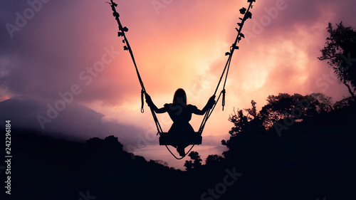 Girl on a swing in the clouds at sunset in the shade © Roman