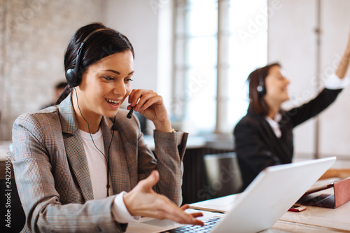 Tableau sur toile Beautiful female customer service talking on the headset with client and smiling