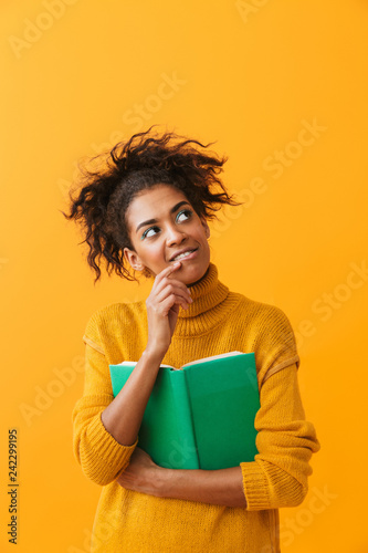 Cheerful african woman wearing sweater holding a book