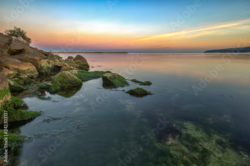 Beauty sea rocky coast with green moss on the stones.