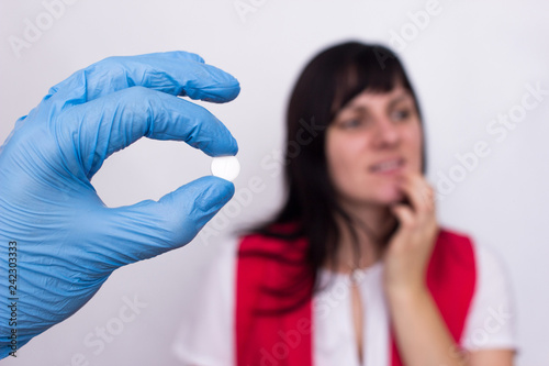 Doctor holds a pill in her hand from oral herpes, the girl holds her lip, pills against herpes, medic photo