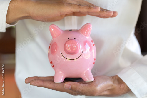 Piggy bank protected by hands, Savings protection, Financial hedging, Risk management.