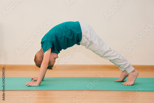Cute little boy is learning to do yoga in the gym