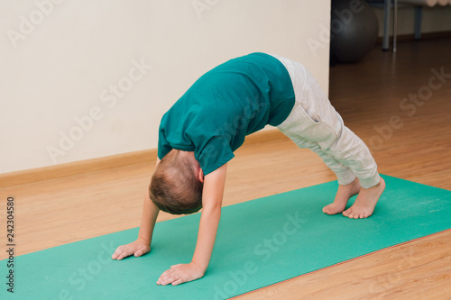 Cute little boy is learning to do yoga in the gym