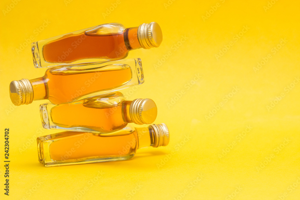 Small bottles with alcohol on a yellow background, close-up, copy space, export