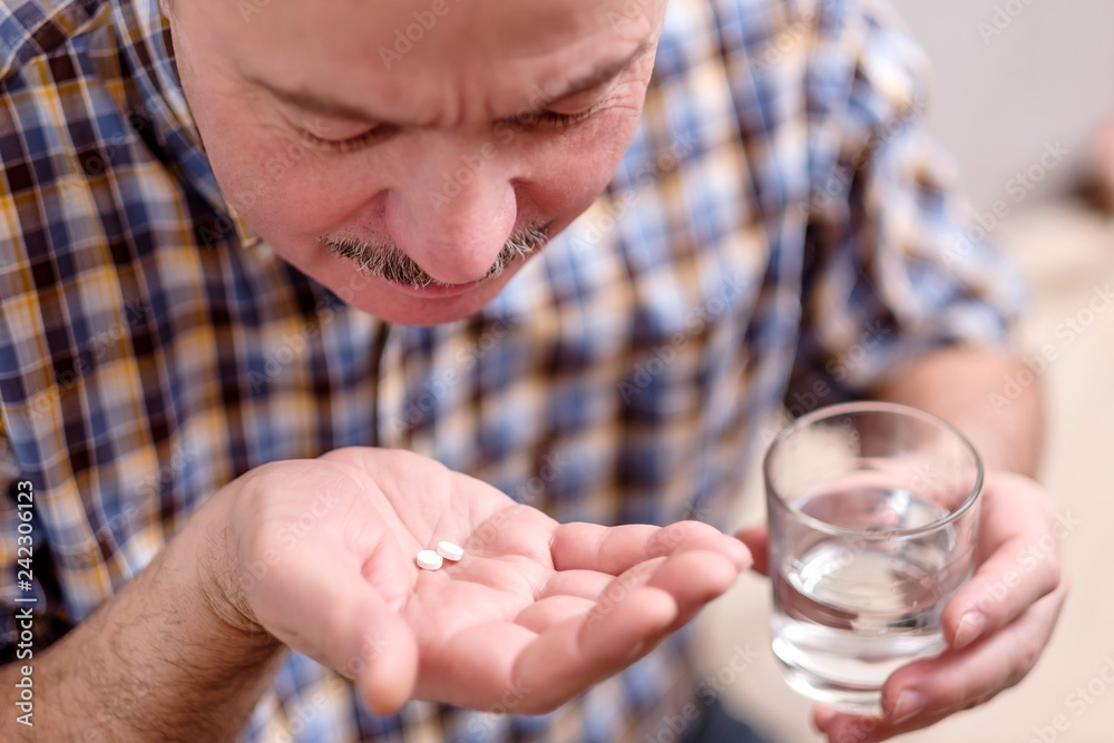 Senior man taking medicine two pills at home Senior man taking medicine two pills at home