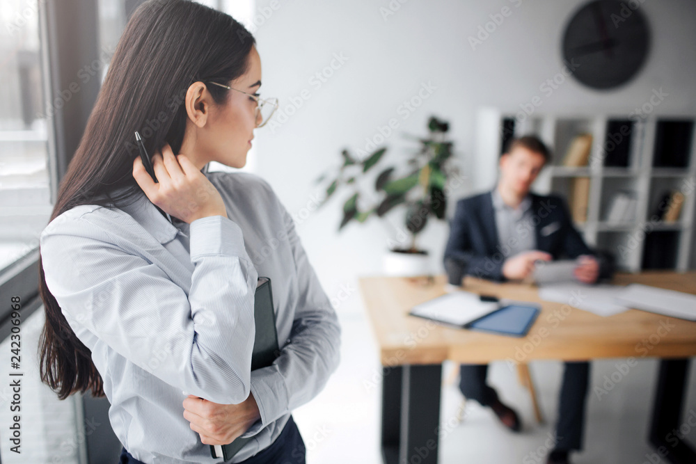 Lovely picture of young confident woman look back at her boss. He sit at table. Guy look at model. She touches her hair with sexual move. Lovely picture of young confident woman look back at her boss. He sit at table. Guy look at model. She touches her hair with sexual move.