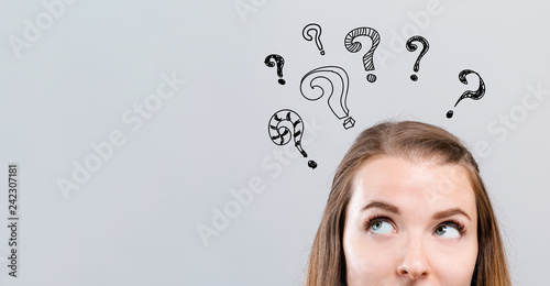 Hand draw question marks with young woman looking upwards on a gray background