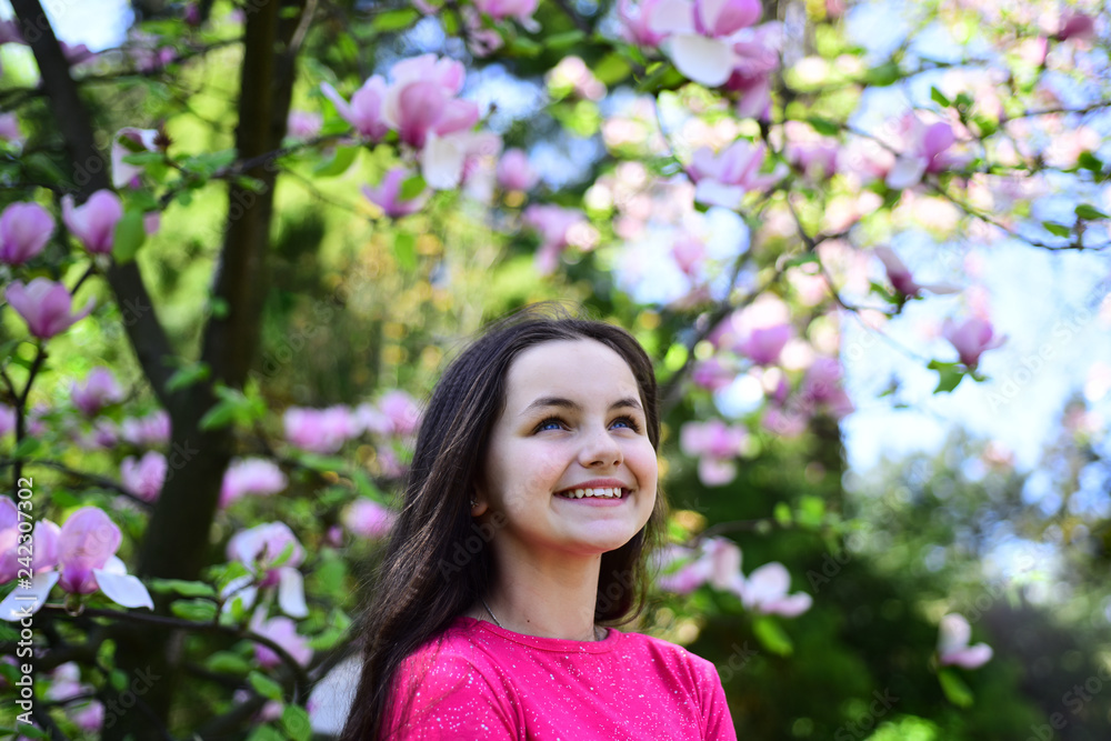 Enjoying springtime. Pretty girl near flowering tree enjoy magnolia blossom. Cute girl happy smiling on spring landscape. Adorable girl smile in park with blossoming flowers. Its spring time Enjoying springtime. Pretty girl near flowering tree enjoy magnolia blossom. Cute girl happy smiling on spring landscape. Adorable girl smile in park with blossoming flowers. Its spring time