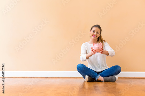 Young woman with a piggy bank against a big interior wall