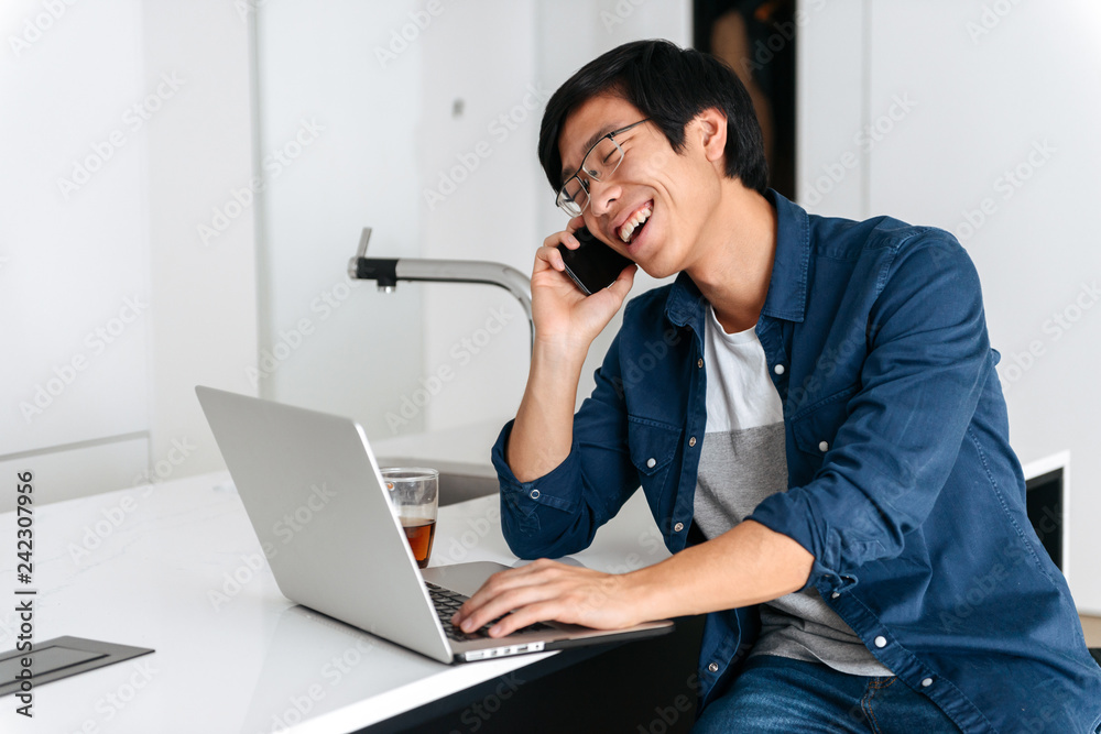 Smiling asian man working on laptop computer Smiling asian man working on laptop computer