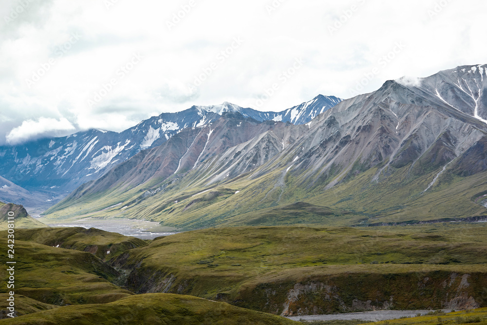 Dry River Bed Running Through Valley Between Mountains In Alaska