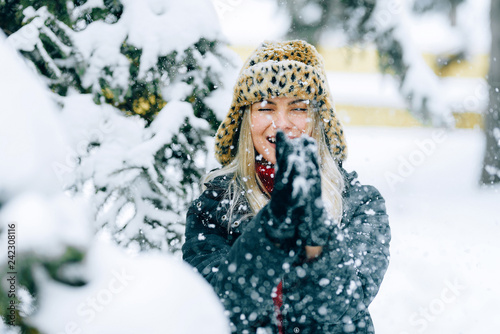 girl in a fashionable winter hat with a leopard print rejoices in the snow