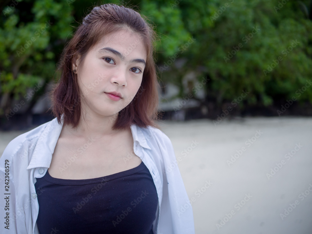 Asian happy girl while standing on tropical beach. Portrait of happiness young woman smiling at sea Thailand. sweet smile. Bright tone. copy space. Asian happy girl while standing on tropical beach. Portrait of happiness young woman smiling at sea Thailand. sweet smile. Bright tone. copy space.