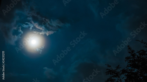 night sky and astronomy on blue background concept from full moon behind the cloud during watch spectacular winter solstice event in december of 2018
