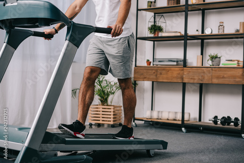Photo cropped view of man workout on treadmill in living room