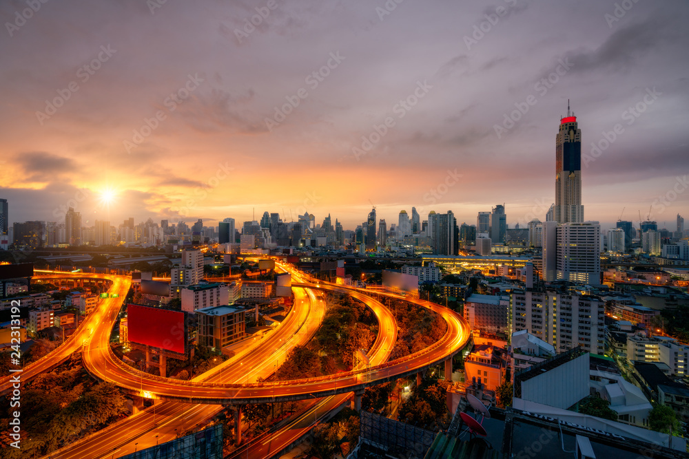 Fototapeta premium Aerial view of Bangkok skyline panorama and skyscraper with light trails on expressway in center of business at capital city. Modern buildings condominium in Bangkok Thailand at sunrise.