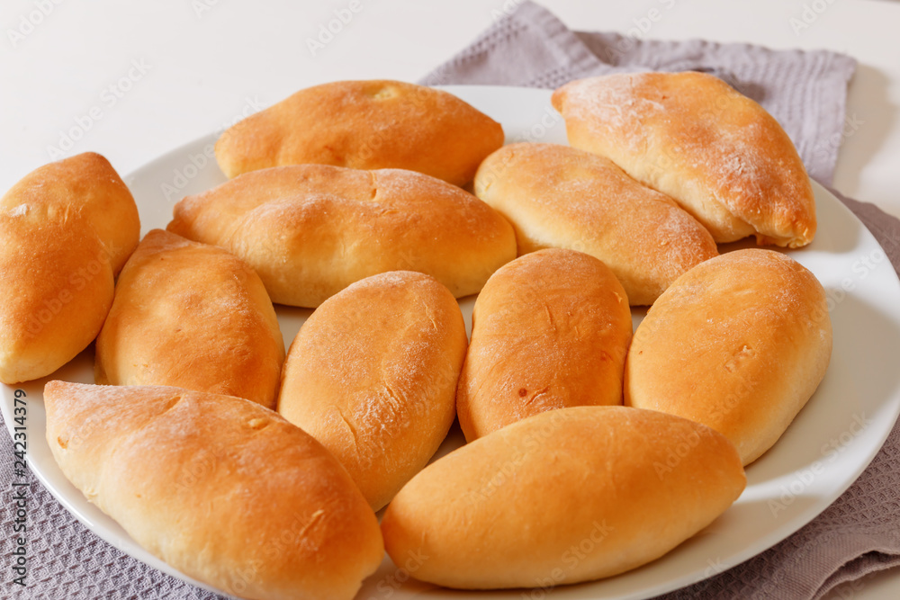 Close-up, homemade cooking. Little pies are lying on a white plate Close-up, homemade cooking. Little pies are lying on a white plate