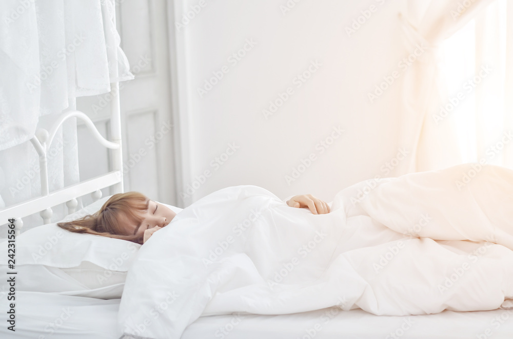 On the bed in the white room.Beautiful woman sleeping in the bedroom.Asian girl sleep well.Sleeping in a white room makes you feel comfortable.Warm tone.