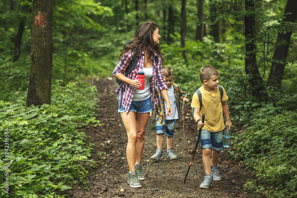 Mother and her little sons hiking trough forest.Spring concept. Mother and her little sons hiking trough forest.Spring concept.