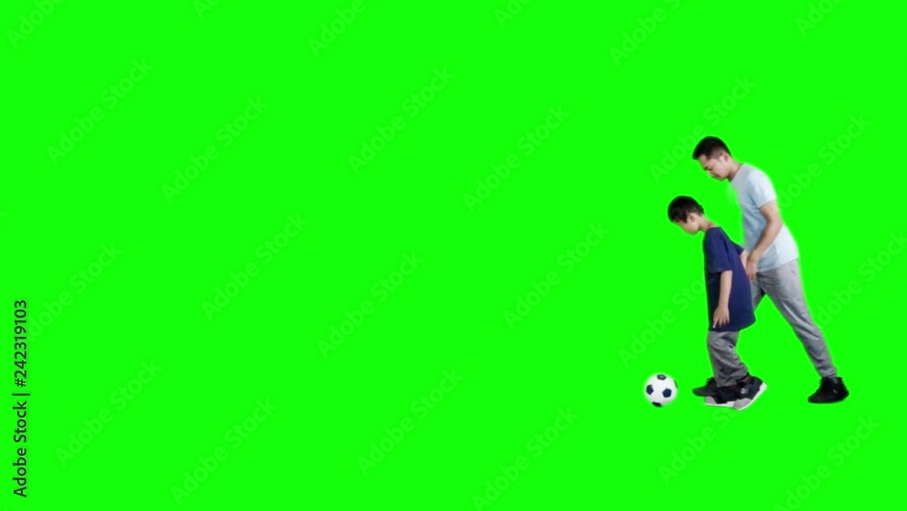 Slow motion of happy little boy playing football with his father in the studio with green screen background Slow motion of happy little boy playing football with his father in the studio with green screen background