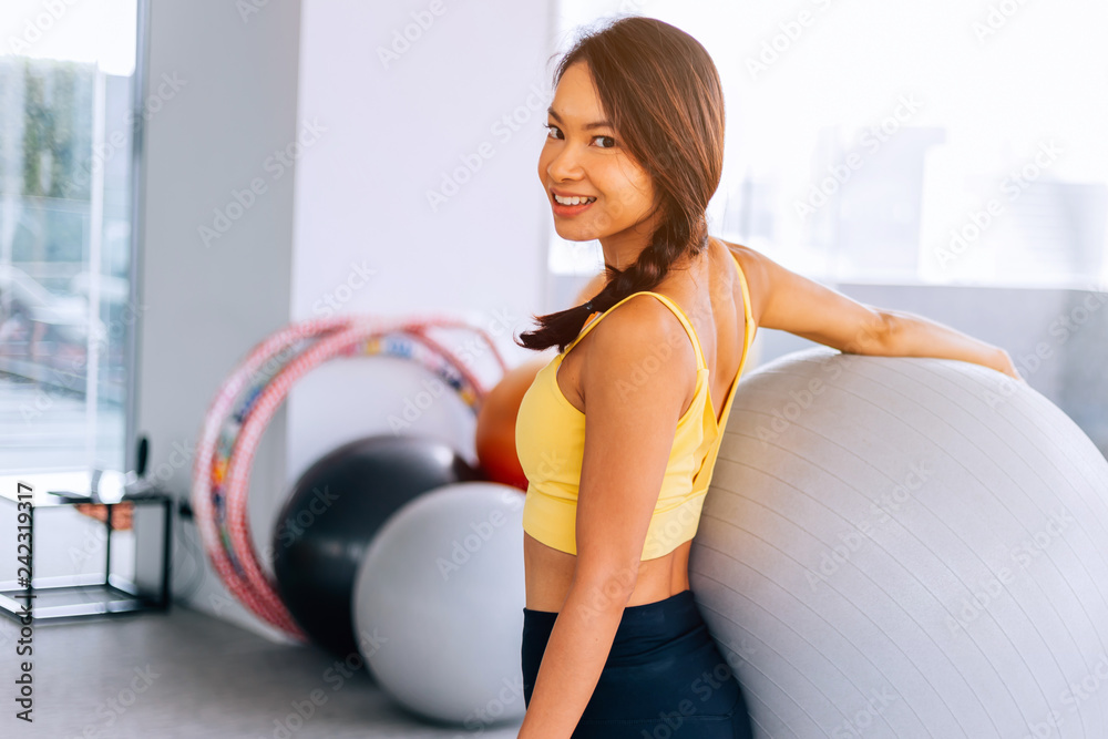 Portrait of young fit Asian woman holding exercise swiss ball and smiling at camera. Lively female fitness model image Portrait of young fit Asian woman holding exercise swiss ball and smiling at camera. Lively female fitness model image
