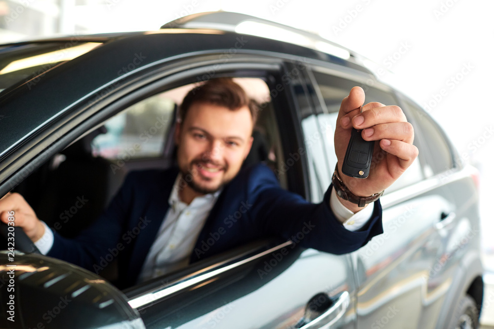 Male driver smiling holds the keys to the car Male driver smiling holds the keys to the car