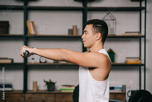 side view of bi-racial man exercising with dumbbells