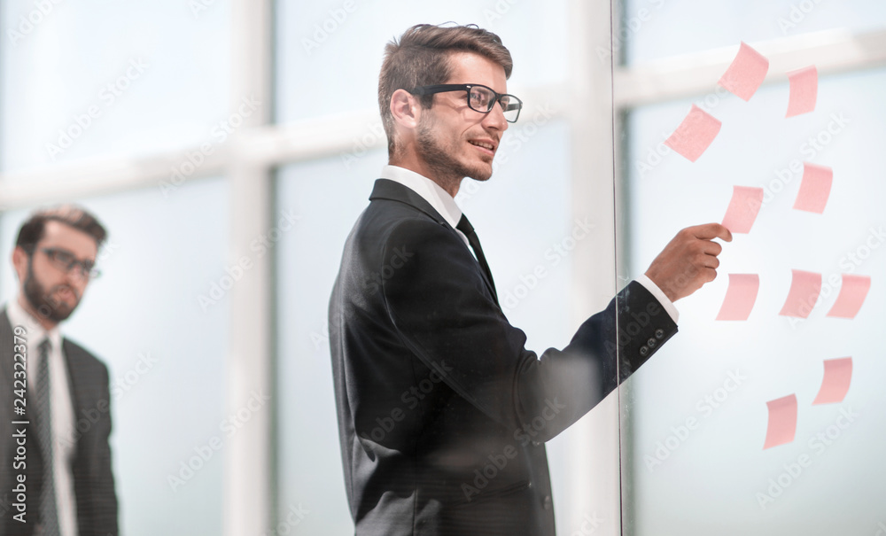 Fototapeta premium employee reads sticky-notes on glass.