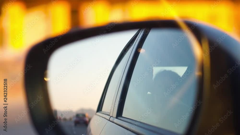 rear view mirror of a moving car with the background being out of focus. The silhouette of the person in teh back seat and the reflections form the movement are visible making this a great shot of rear view mirror of a moving car with the background being out of focus. The silhouette of the person in teh back seat and the reflections form the movement are visible making this a great shot of