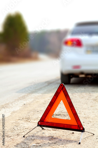 White car and a red triangle warning sign on the road