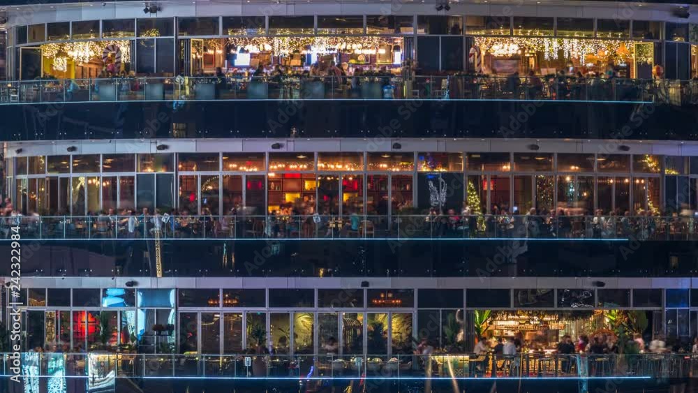 Circular building with different restaurants at each floor in the heart of Dubai Marina district night timelapse.