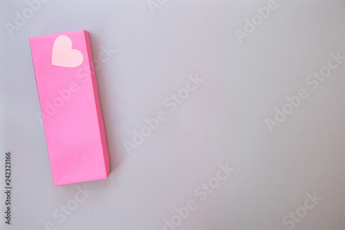 Big pink gift box with a heart of love on the silver gray metal background