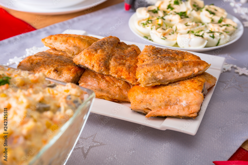 Christmas dinner table with fried salmon fillets and eggs mayonnaise