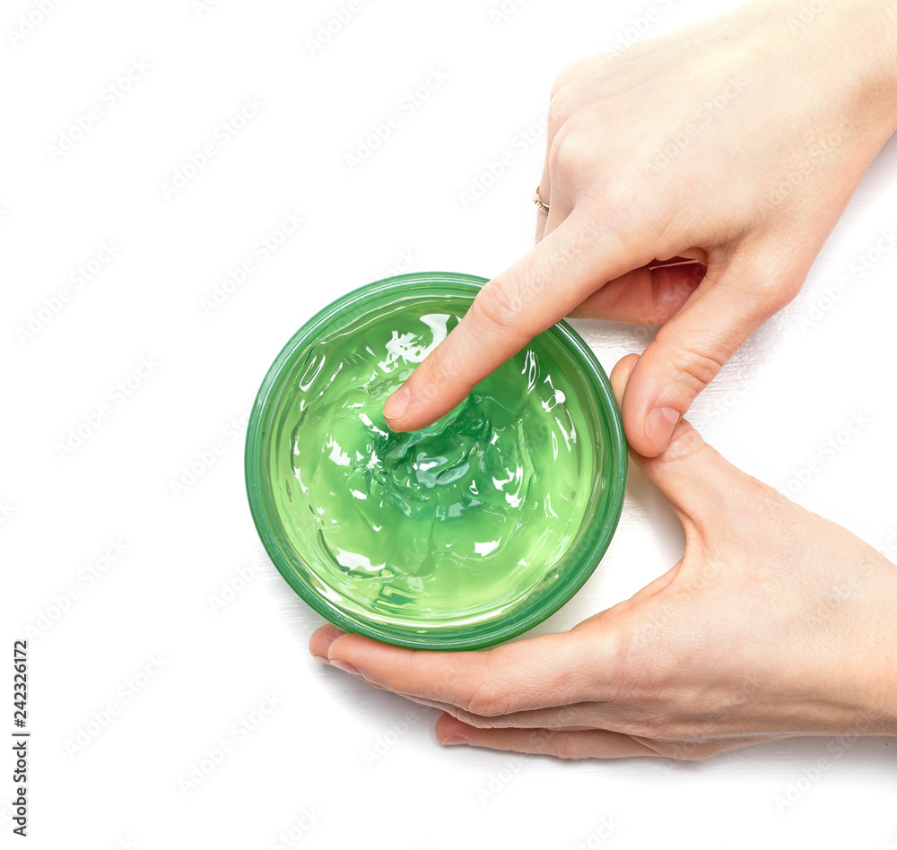 Aloe Vera Gel on a female hand which is scooping it from a jar on white  background, top of view. Aloe Vera is natural remedy for sunburn relief.  Natural alternative medicine. Stock