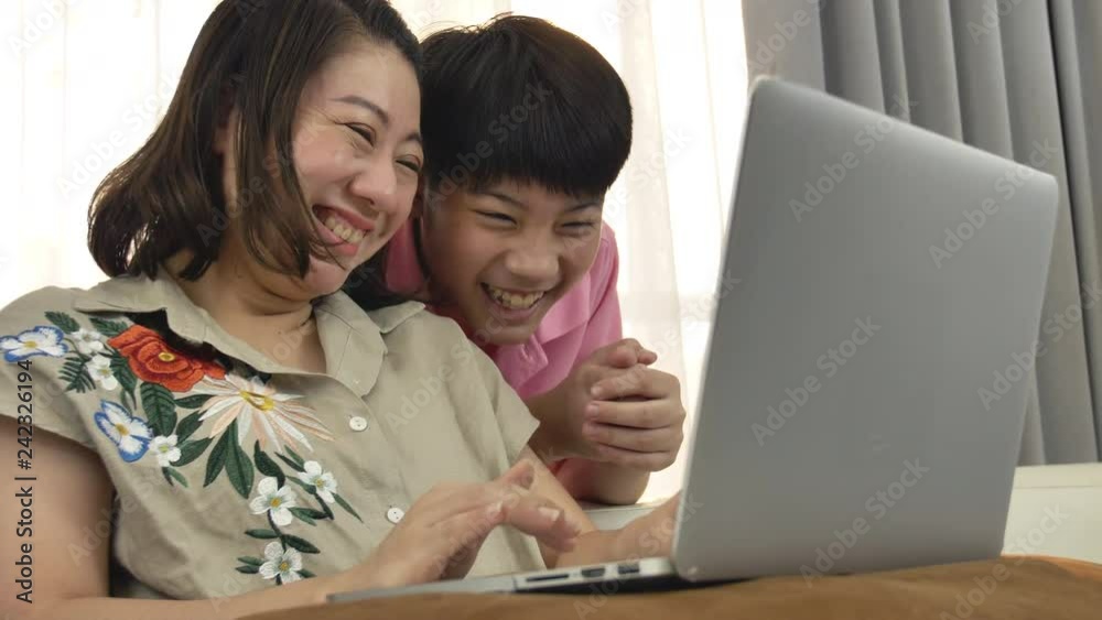 4K Family lifestyle is playing computer games. Asian Mother and son watching on laptop computer with smile face. 4K Family lifestyle is playing computer games. Asian Mother and son watching on laptop computer with smile face.