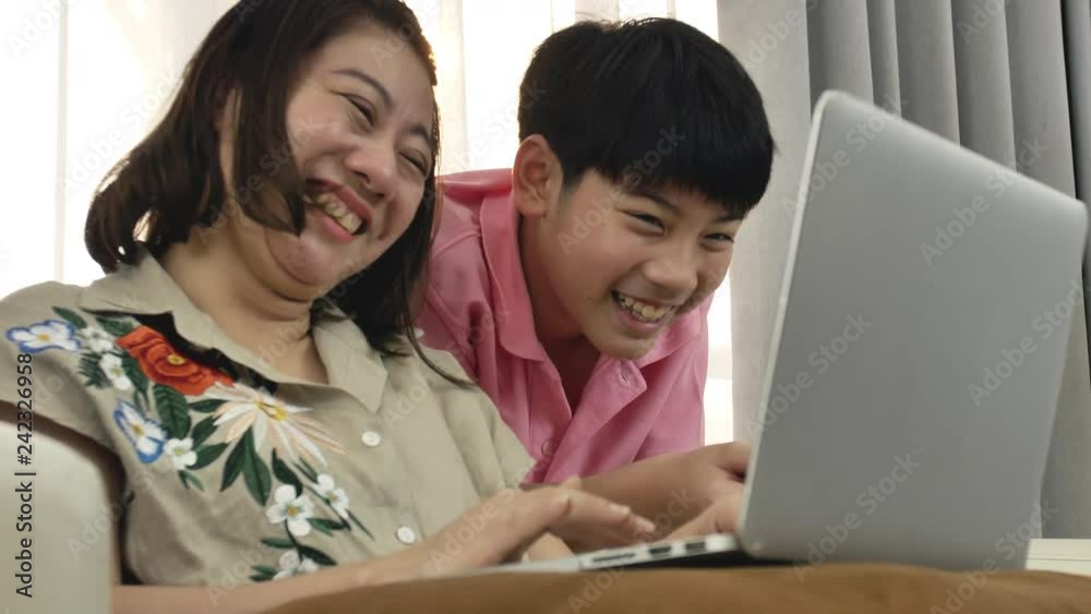 4K Family lifestyle is playing computer games. Asian Mother and son watching on laptop computer with smile face. 4K Family lifestyle is playing computer games. Asian Mother and son watching on laptop computer with smile face.
