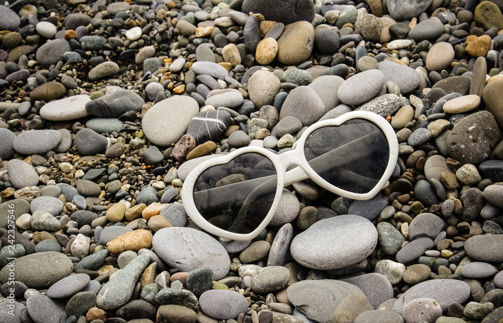 White sunglasses in the shape of a heart lie on the seashore White sunglasses in the shape of a heart lie on the seashore