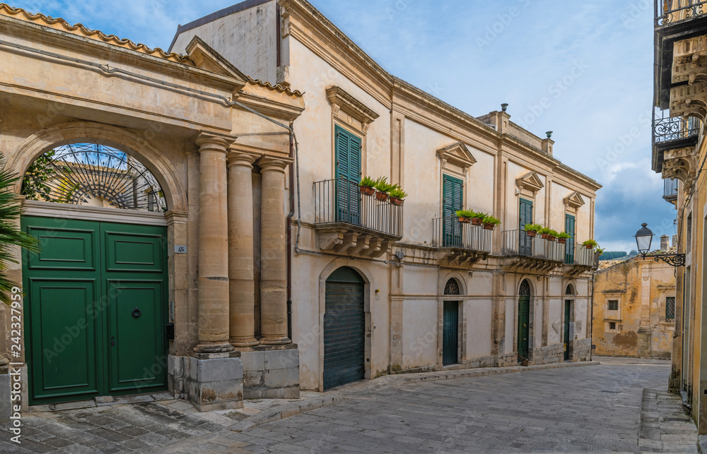 Narrow italian street with big green door and windows in the ancient baroque town Ragusa, Sicily, Italy