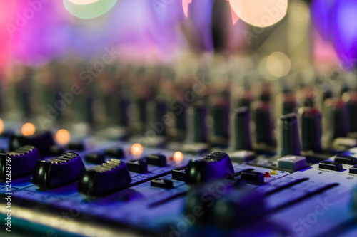 Selective focus on knops of electronic sound mixer in the foreground of the outdoor party music with bokeh.