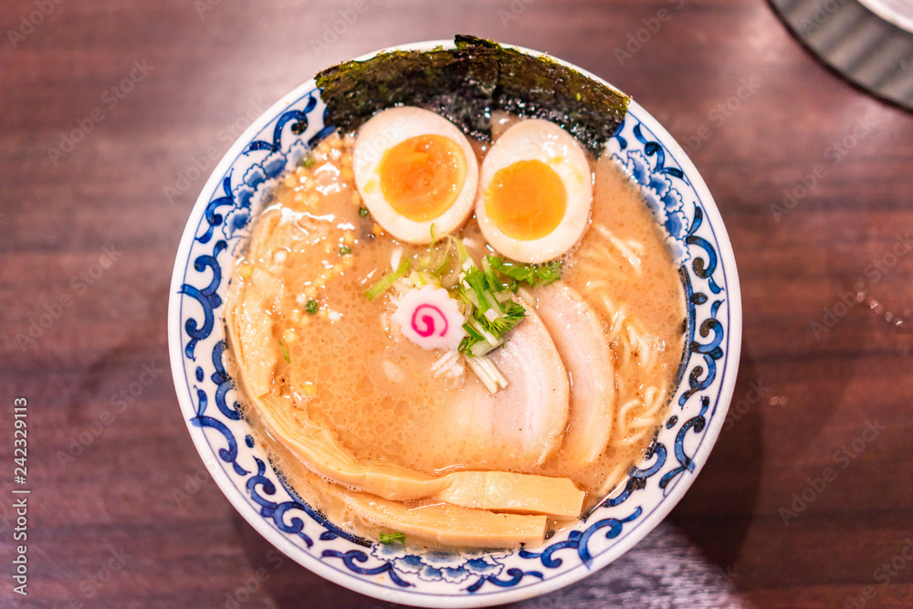 Japanese ramen soup with chicken, egg, chives and sprout on dark wooden background