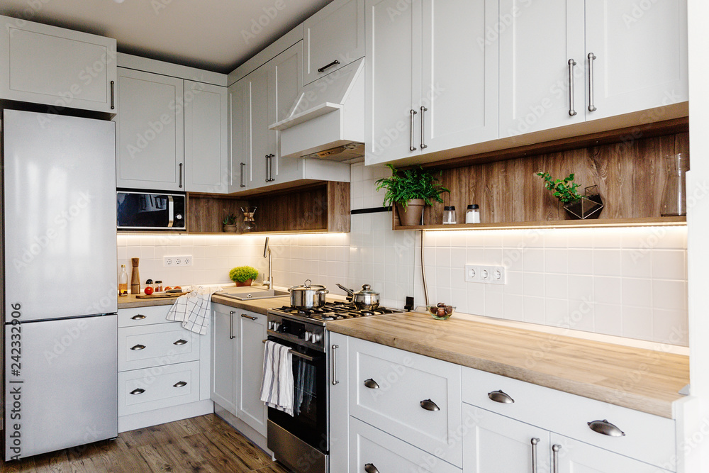 Luxury modern kitchen furniture in grey color and steel oven,fridge, sink, wooden tabletop, pots,. Gray cabinets in scandinavian style. Home renovation. Stylish kitchen interior design. Luxury modern kitchen furniture in grey color and steel oven,fridge, sink, wooden tabletop, pots,. Gray cabinets in scandinavian style. Home renovation. Stylish kitchen interior design.