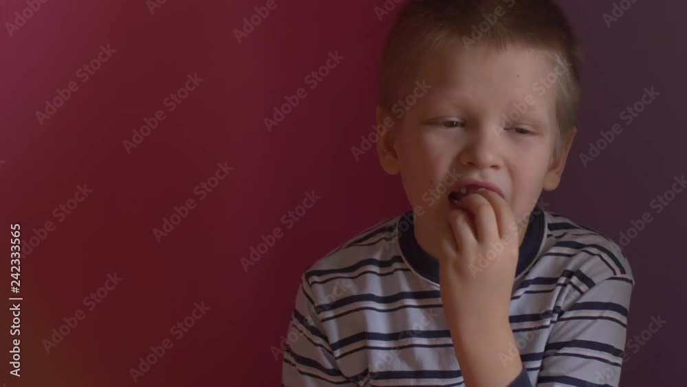 Cute baby shows dropped baby tooth. Boy smiles with toothless mouth. Striped home pajamas, proton purple background Cute baby shows dropped baby tooth. Boy smiles with toothless mouth. Striped home pajamas, proton purple background