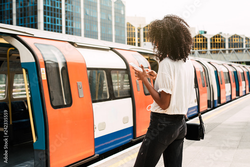 Black woman using mobile phone at london underground