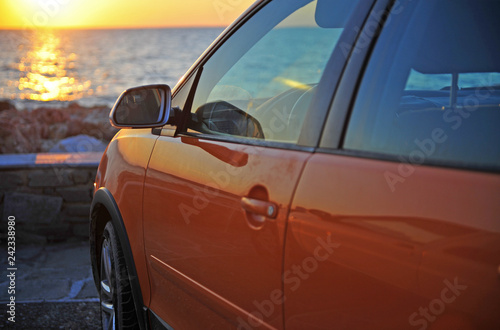 Modern red car at sea on sunset