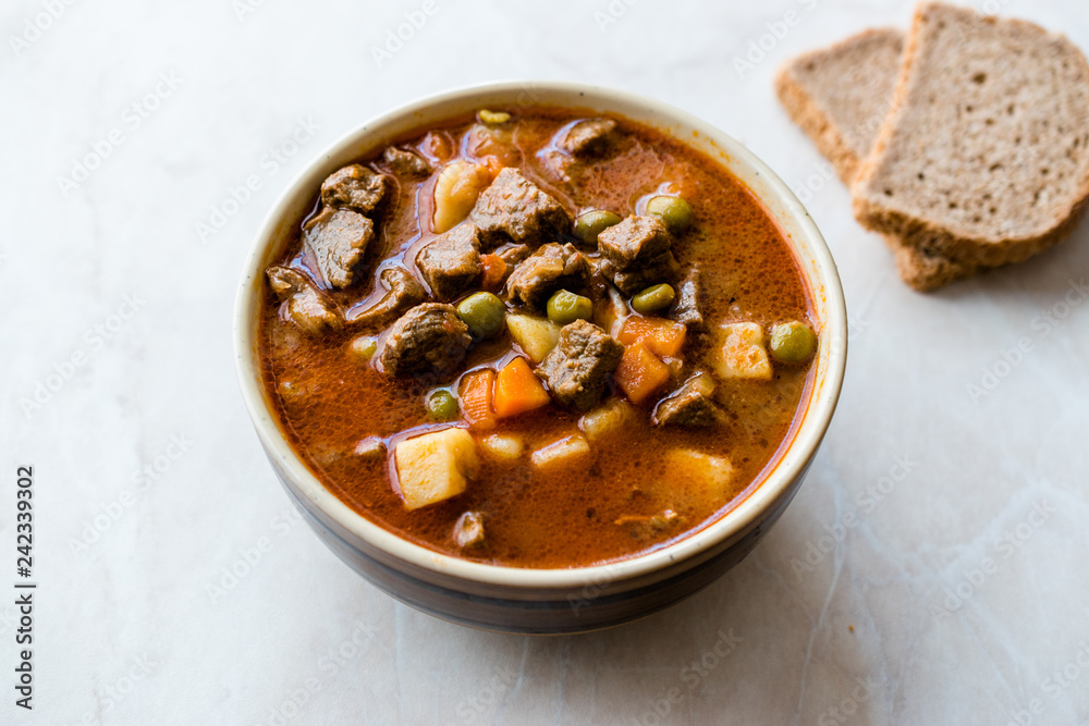 Tasty Hungarian Hot Goulash Soup Bograch or Gulas Lamb Meat Stew with Whole Grain Bread on Wooden Surface at Restaurant. Traditional Food. Tasty Hungarian Hot Goulash Soup Bograch or Gulas Lamb Meat Stew with Whole Grain Bread on Wooden Surface at Restaurant. Traditional Food.